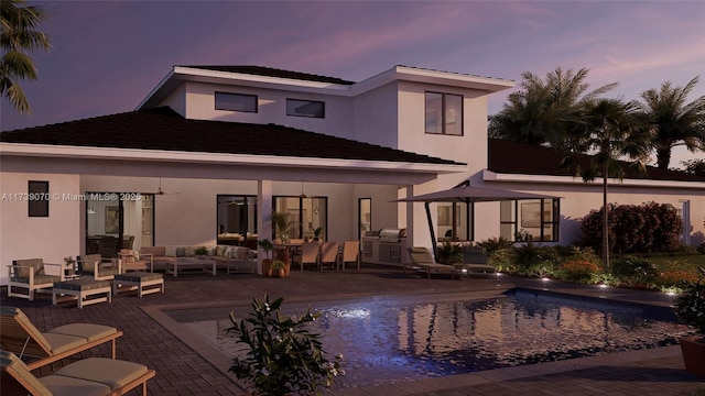 rear view of house with an outdoor pool, a ceiling fan, a patio area, outdoor lounge area, and stucco siding