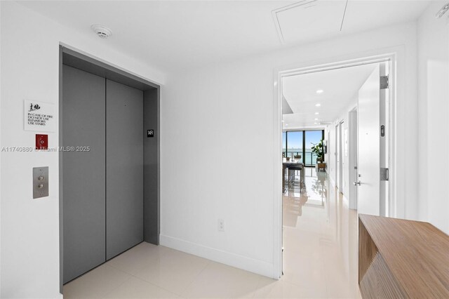 corridor with elevator and light tile patterned floors