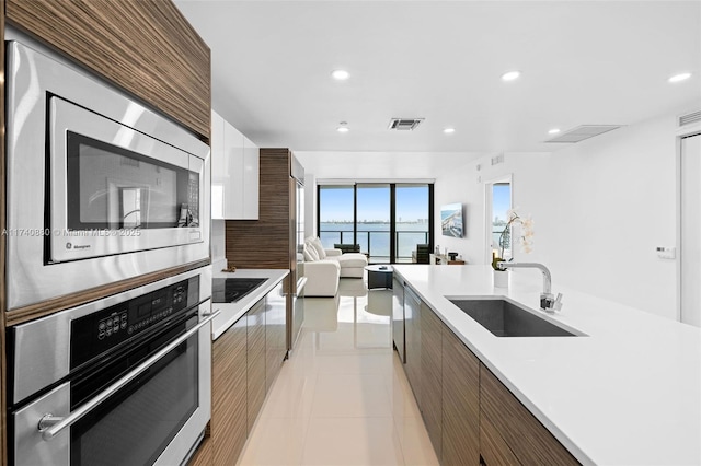 kitchen featuring a water view, appliances with stainless steel finishes, sink, and light tile patterned floors