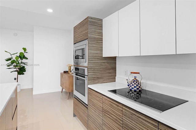 kitchen featuring stainless steel appliances, light tile patterned flooring, and white cabinets