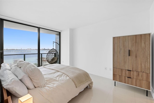 bedroom with access to exterior, floor to ceiling windows, and a water view