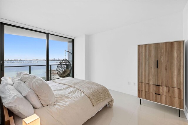 bedroom featuring light tile patterned floors, access to outside, expansive windows, and a water view