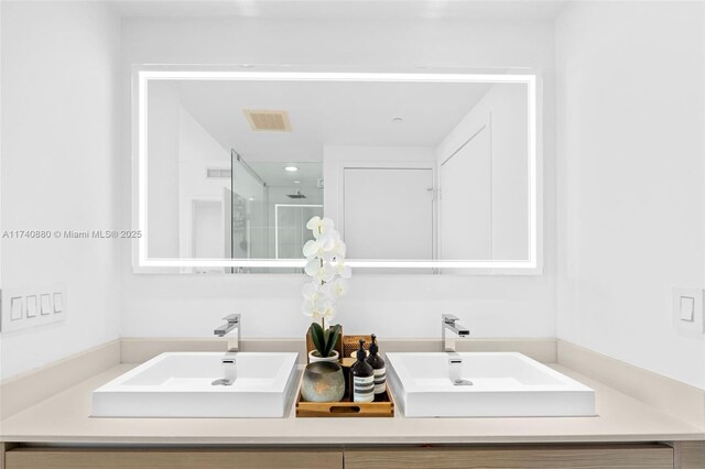 bathroom with a shower with door, vanity, and tile patterned floors