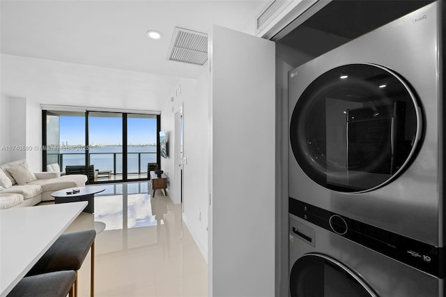 washroom with a water view, stacked washer / dryer, and light tile patterned flooring