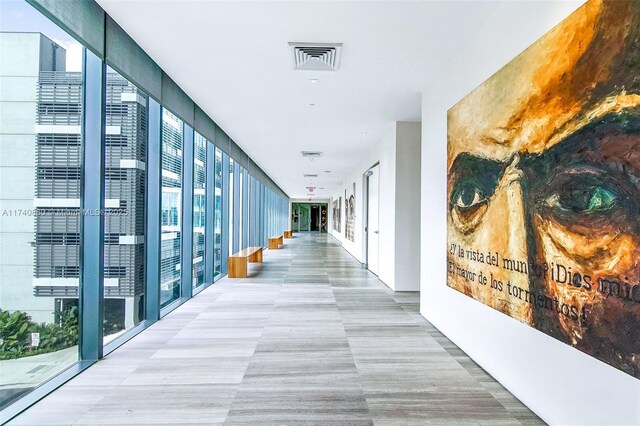 gym with hardwood / wood-style flooring, a water view, and a wall of windows