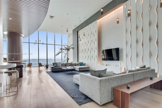 living room featuring expansive windows, a towering ceiling, and light wood-type flooring