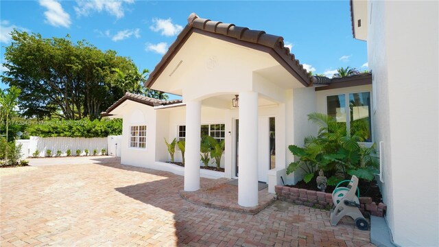 691 Ridgewood Rd, Key Biscayne, FL 33149 - rear view of property featuring fence, a patio, stucco siding, and a tile roof
