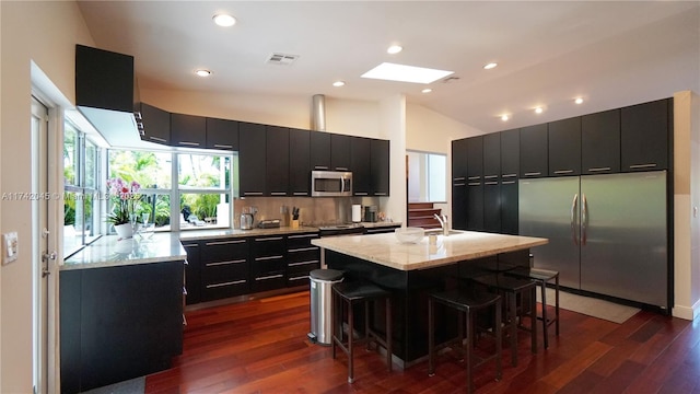 691 Ridgewood Rd, Key Biscayne, FL 33149 - kitchen with a breakfast bar area, dark cabinets, appliances with stainless steel finishes, and visible vents