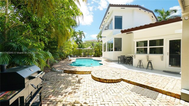 691 Ridgewood Rd, Key Biscayne, FL 33149 - back of property with a tiled roof, a fenced in pool, a patio area, and stucco siding