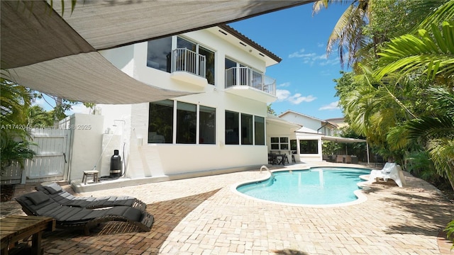 691 Ridgewood Rd, Key Biscayne, FL 33149 - rear view of property featuring a balcony, a patio, an outdoor pool, stucco siding, and a gate