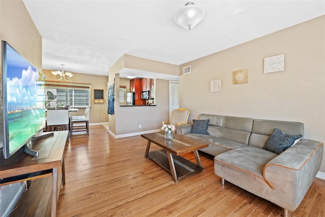 living room with light hardwood / wood-style flooring and a notable chandelier