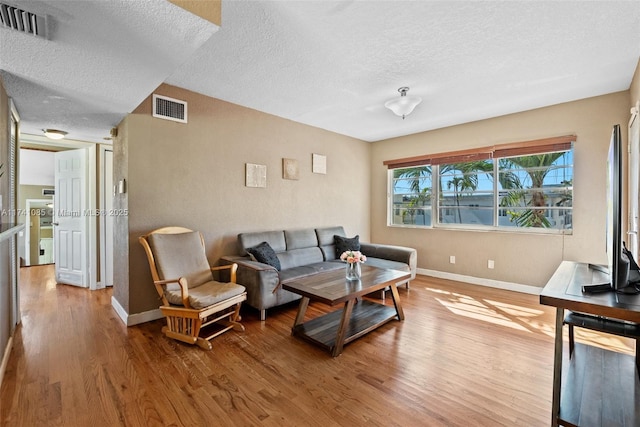 living room featuring light hardwood / wood-style flooring and a textured ceiling