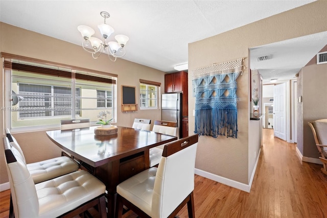 dining space with a notable chandelier and light hardwood / wood-style flooring