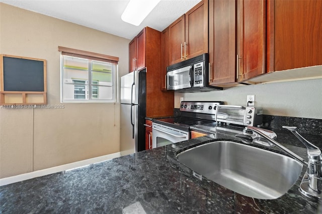 kitchen featuring stainless steel appliances, sink, and dark stone counters