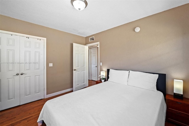 bedroom with dark wood-type flooring and a closet