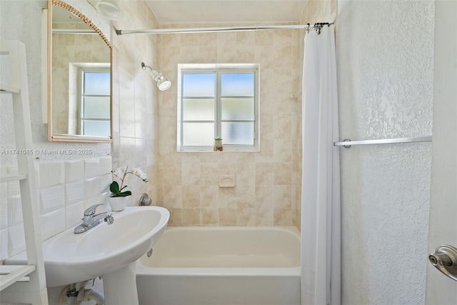 bathroom featuring tile walls, sink, and shower / bath combo with shower curtain