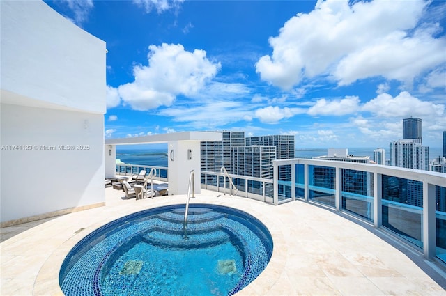 view of swimming pool featuring a community hot tub, a patio, and a water view