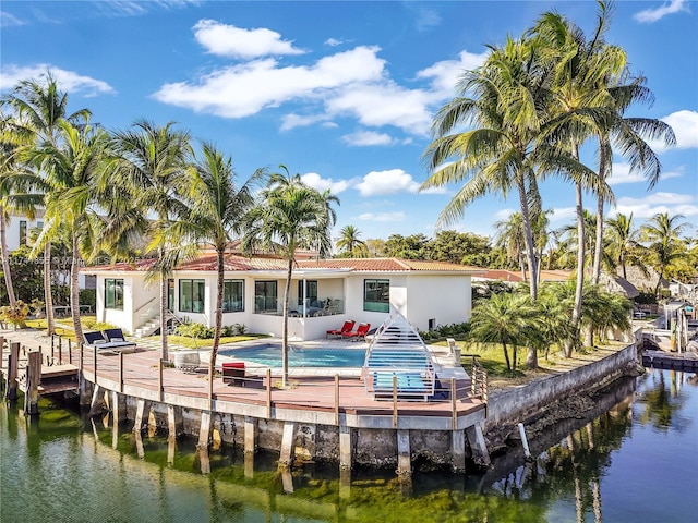 back of property featuring stucco siding, a tile roof, and a water view