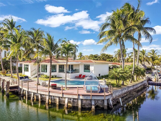 rear view of house featuring a patio, an outdoor pool, a water view, stucco siding, and a tile roof