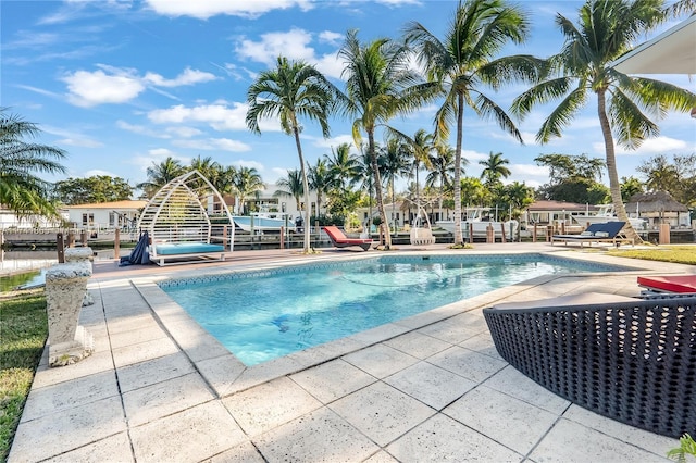 view of pool with a patio and a dock