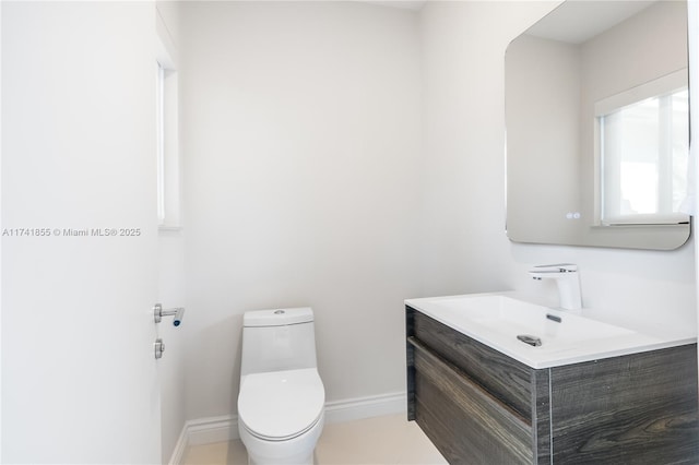 bathroom with toilet, vanity, and baseboards