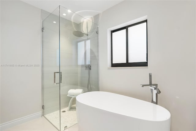 full bathroom with a shower stall, baseboards, and a freestanding tub