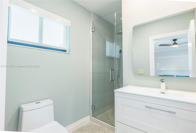 bathroom with a shower stall, toilet, vanity, and baseboards