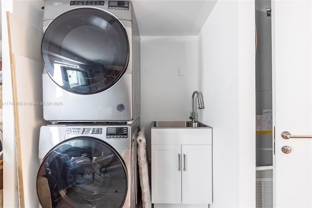 washroom with a sink, cabinet space, and stacked washer / dryer