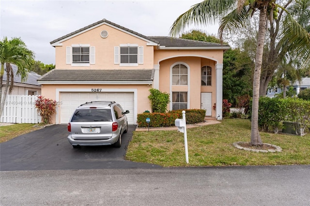 view of front of property with a front lawn, fence, driveway, and stucco siding