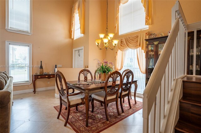 tiled dining area featuring a high ceiling and a notable chandelier