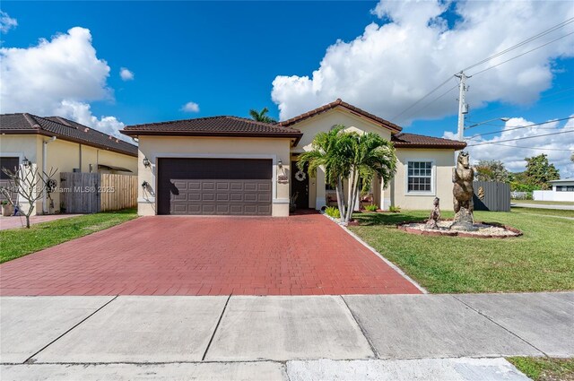 mediterranean / spanish home featuring a garage and a front lawn