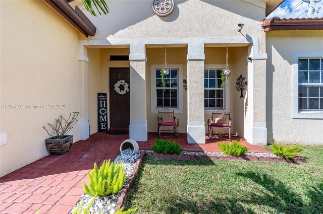 view of exterior entry featuring a lawn