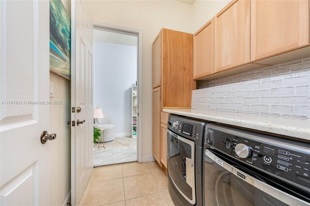 laundry area with light tile patterned floors, cabinets, and washing machine and clothes dryer