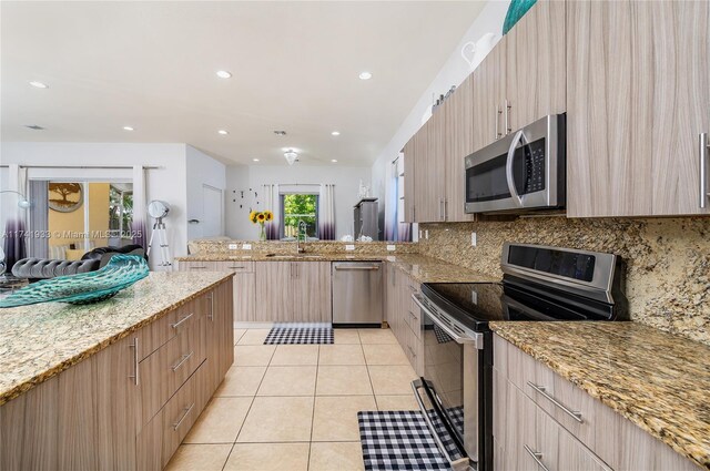 kitchen with appliances with stainless steel finishes, sink, decorative backsplash, light tile patterned floors, and light stone countertops