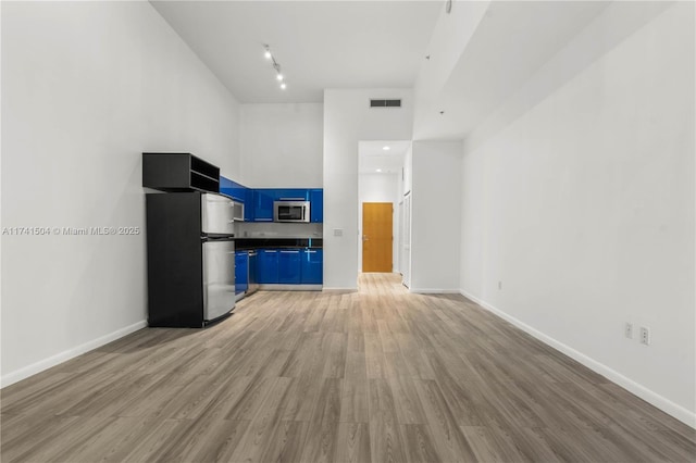 unfurnished living room featuring a towering ceiling and light hardwood / wood-style flooring