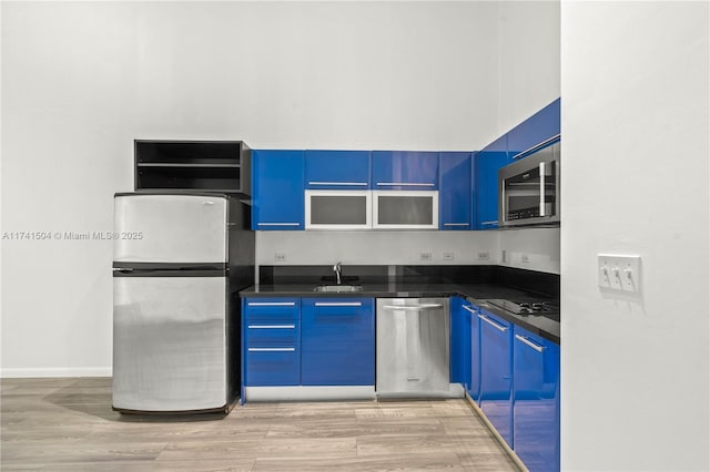 kitchen featuring sink, blue cabinetry, light hardwood / wood-style floors, and appliances with stainless steel finishes