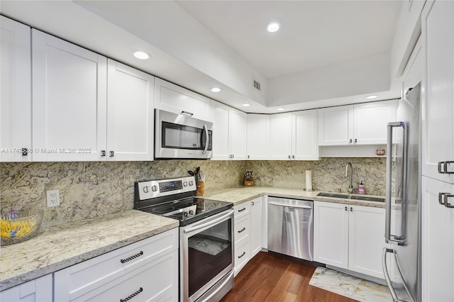 kitchen featuring white cabinetry, sink, light stone counters, stainless steel appliances, and dark wood-type flooring