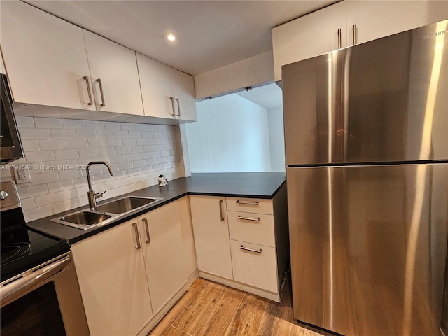 kitchen with sink, backsplash, light hardwood / wood-style flooring, and stainless steel appliances