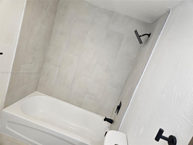 bathroom featuring toilet and tiled shower / bath combo