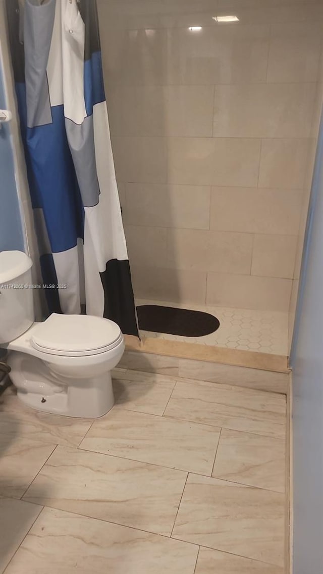 bathroom with toilet and a shower with shower curtain