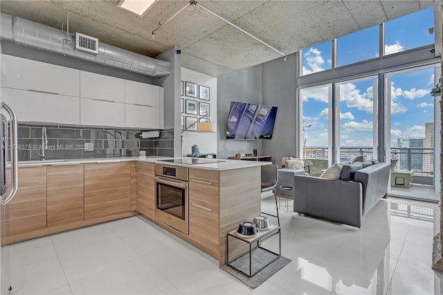 kitchen featuring sink, stainless steel oven, light tile patterned floors, black electric stovetop, and backsplash