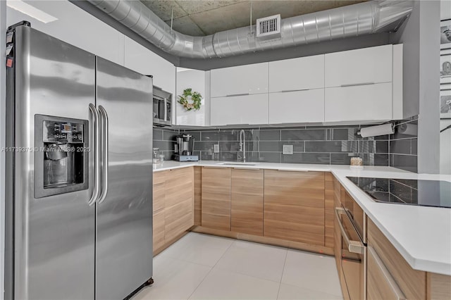 kitchen featuring sink, appliances with stainless steel finishes, white cabinetry, backsplash, and light tile patterned flooring