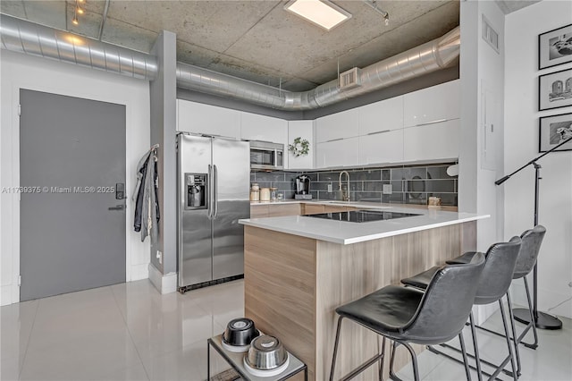 kitchen featuring a kitchen bar, white cabinetry, tasteful backsplash, a kitchen island, and stainless steel appliances