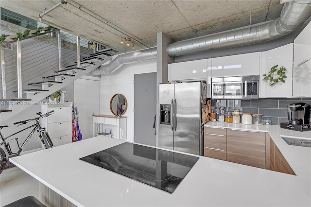 kitchen featuring appliances with stainless steel finishes, white cabinets, and backsplash