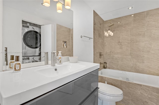 full bathroom with stacked washer / dryer, toilet, tiled shower / bath combo, and vanity