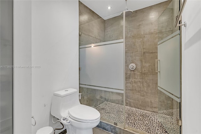 bathroom featuring a shower with shower door and toilet