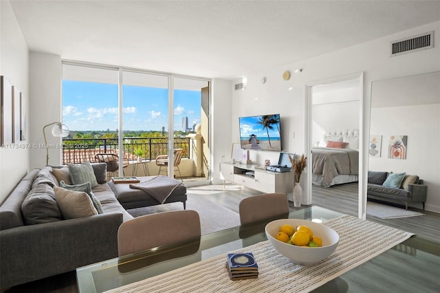 living area featuring floor to ceiling windows, visible vents, and light wood-style flooring