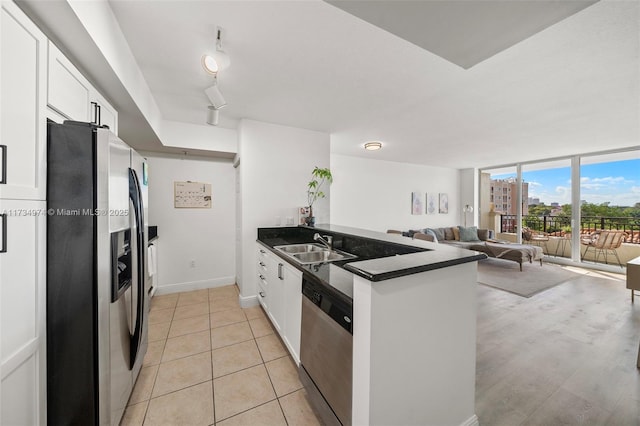 kitchen featuring stainless steel appliances, kitchen peninsula, sink, and white cabinets