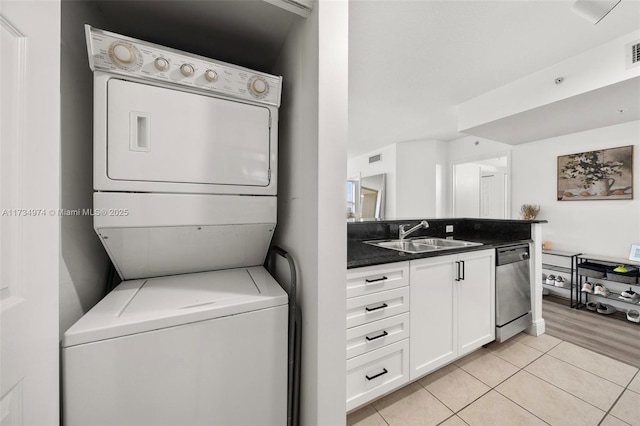 washroom featuring sink, light tile patterned floors, and stacked washer / drying machine