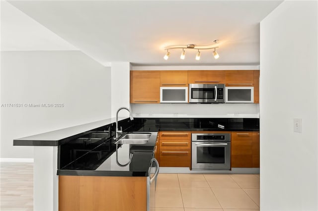 kitchen with stainless steel appliances, sink, light tile patterned floors, and kitchen peninsula